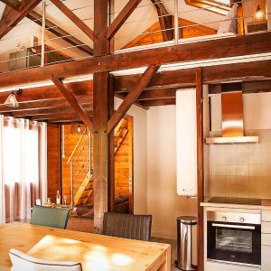 Hébergement insolite en bois à Midi-Pyrénées, avec poutres apparentes et cuisine moderne.