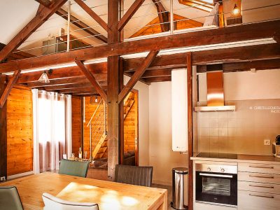Hébergement insolite en bois à Midi-Pyrénées, avec poutres apparentes et cuisine moderne.