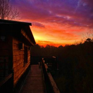 Cabane en bois à Midi-Pyrénées, avec un coucher de soleil éclatant en arrière-plan.