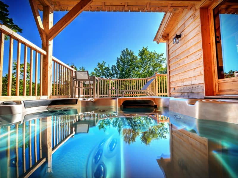Chalet en bois avec jacuzzi, offrant une vue dégagée sur la nature environnante.