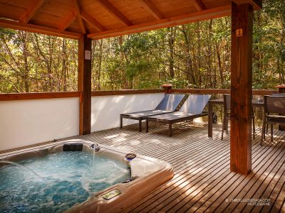 Hébergement insolite en Midi-Pyrénées avec jacuzzi et chaises longues en bois.