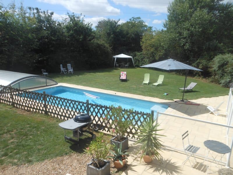 Maison avec piscine, jardin verdoyant et chaises longues pour se détendre.