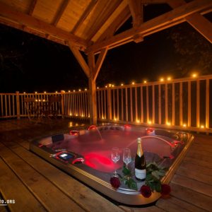 Hébergement insolite en Midi-Pyrénées avec jacuzzi romantique sous une pergola illuminée.