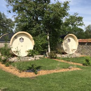 Hébergement insolite en Bourgogne : deux cabanes en bois rond entourées de verdure.