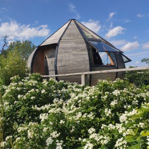 Hébergement insolite en forme de cabane, entouré de fleurs blanches en Nouvelle-Aquitaine.