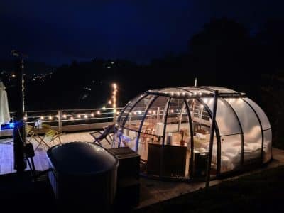 Hébergement insolite en bulle transparente, illuminée, avec vue nocturne sur la vallée.