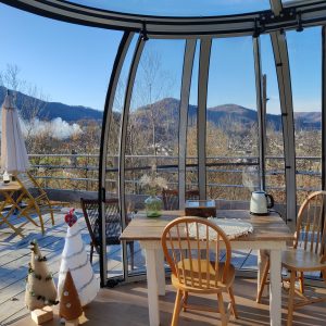 Hébergement insolite en verre avec vue panoramique sur les montagnes et la nature.