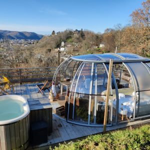 Hébergement insolite en bulle transparente avec jacuzzi et vue panoramique sur la vallée.