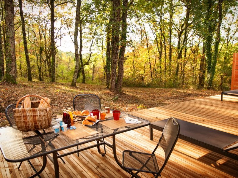 Hébergement insolite en Midi-Pyrénées avec terrasse en bois et vue sur la forêt.