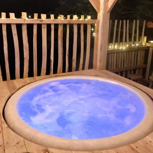 Hébergement insolite en Île-de-France avec jacuzzi lumineux sous un abri en bois.