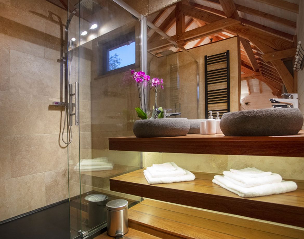 Salle de bain moderne dun hébergement insolite en Languedoc-Roussillon, avec fleurs et bois.
