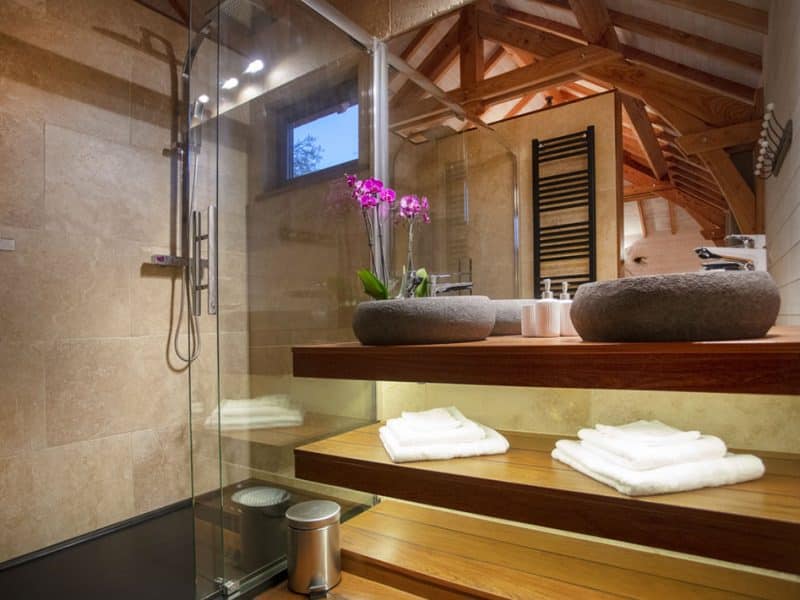 Salle de bain moderne dun hébergement insolite en Languedoc-Roussillon, avec fleurs et bois.