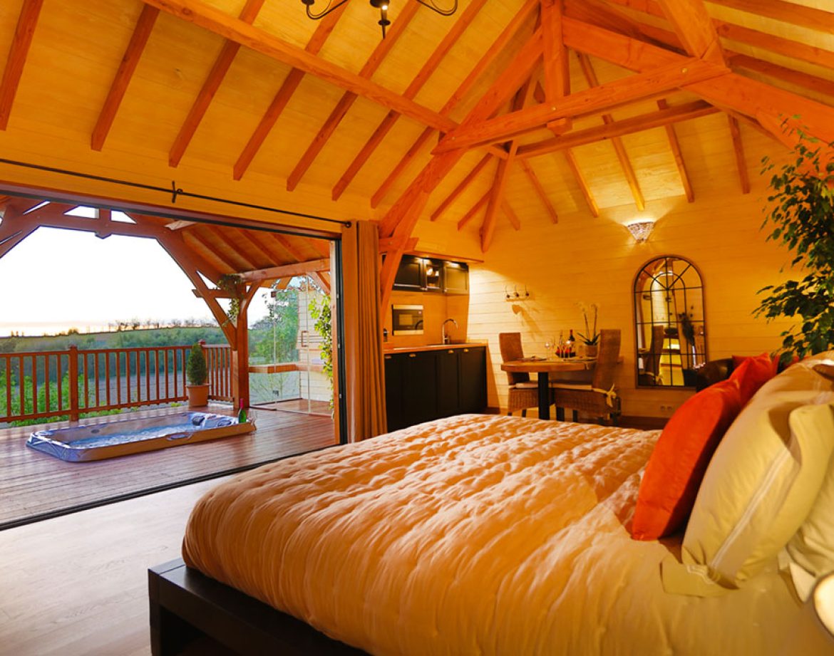Chalet en bois avec vue panoramique, lit douillet et terrasse ensoleillée.