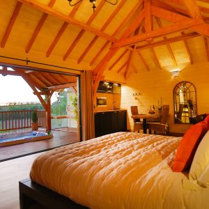Chalet en bois avec vue panoramique, lit douillet et terrasse ensoleillée.