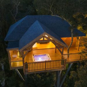 Cabane perchée dans les arbres avec jacuzzi sur la terrasse, au cœur de la nature.