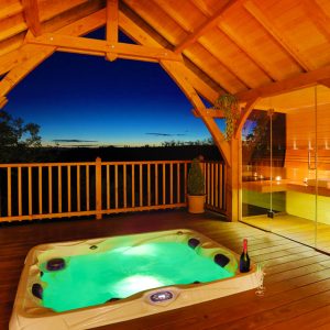 Cabane en bois avec jacuzzi, offrant une vue imprenable sur le coucher de soleil.