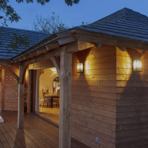 Cabane en bois avec jacuzzi, entourée de verdure au crépuscule.
