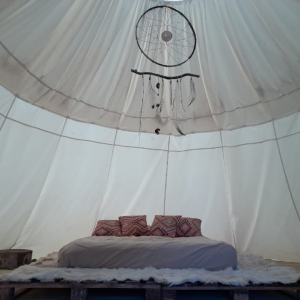 Tente suspendue en Bourgogne, avec un lit douillet et des coussins colorés.