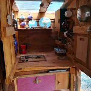 Cuisine en bois dun hébergement insolite en Basse-Normandie, décorée de vaisselle colorée.