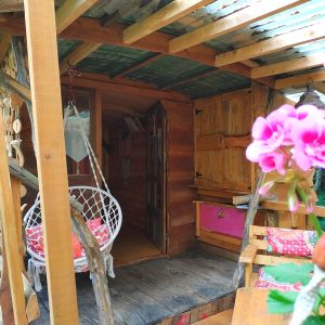 Cabane en bois à Basse-Normandie avec balançoire et fleurs colorées.