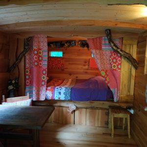 Cabane en bois colorée avec lit douillet et décor floral accueillant.