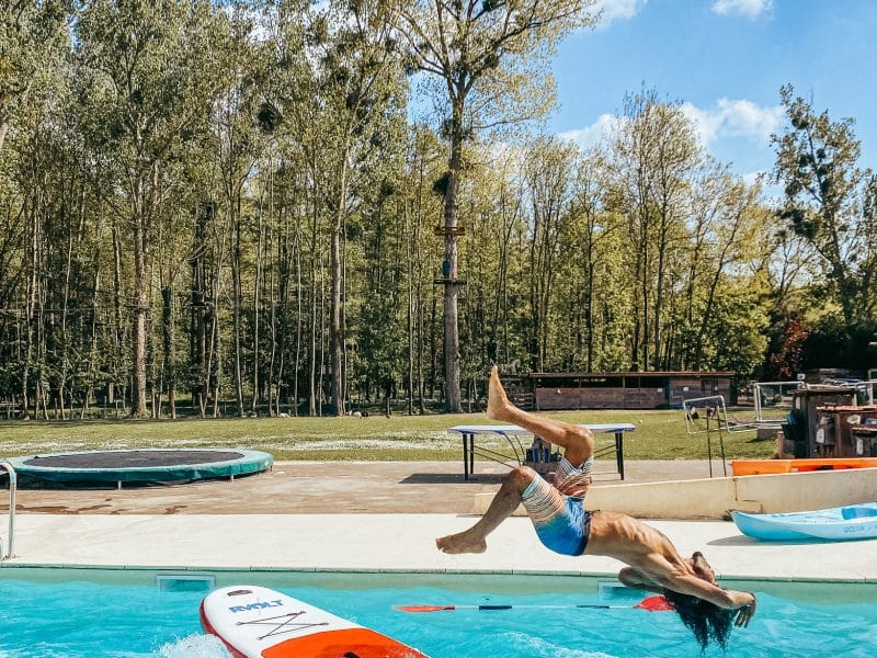 Hébergement touristique avec piscine, un homme plongeant joyeusement dans leau.