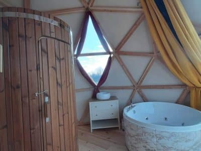 Dôme insolite avec baignoire spa et sauna en bois, ambiance chaleureuse et moderne.