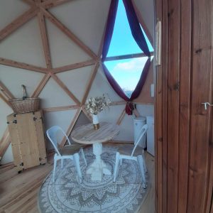 Dôme géodésique au Centre, intérieur cosy avec table ronde et décor chaleureux.