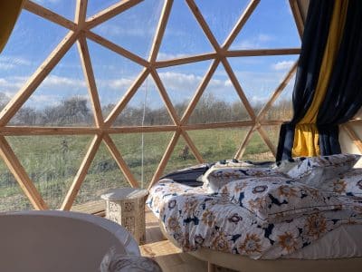 Dôme géodésique avec vue panoramique, lit douillet et décor floral.