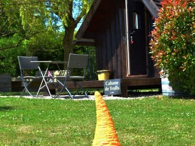Cabane de trolls en Nouvelle-Aquitaine, avec un gnome orange et une terrasse accueillante.