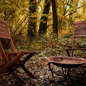 Hébergement insolite en Île-de-France avec chaises en bois et un brasero au milieu de la nature.