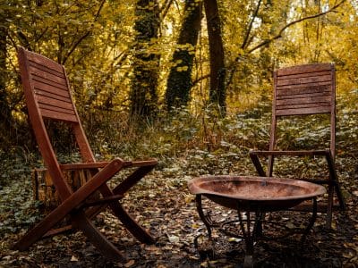 Hébergement insolite en Île-de-France avec chaises en bois et un brasero au milieu de la nature.