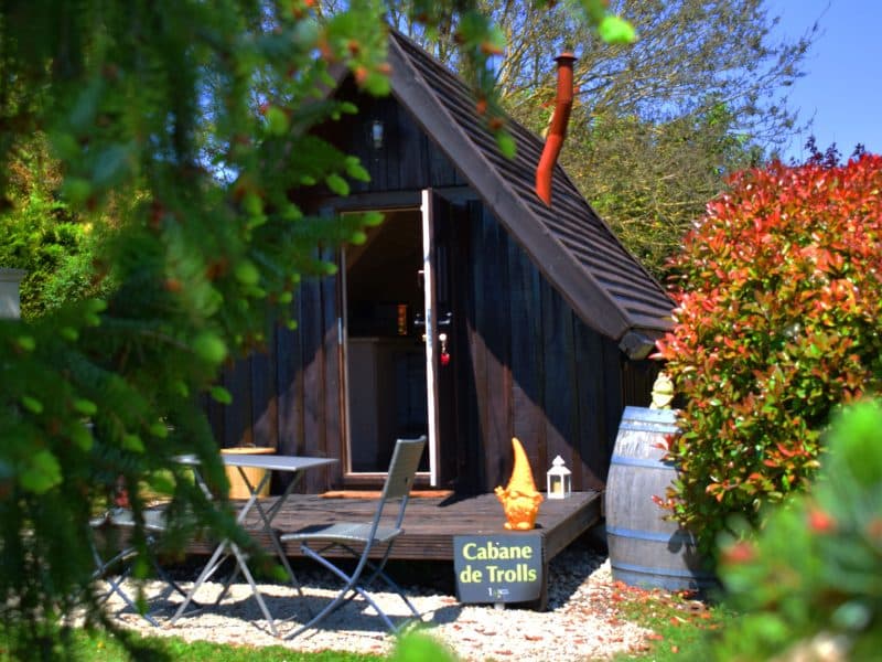 Cabane de trolls en Nouvelle-Aquitaine, entourée de verdure et décorée dun élément coloré.