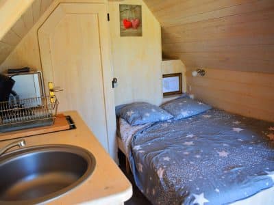 Chalet en bois cosy avec lit étoilé et kitchenette, idéal pour un séjour romantique.