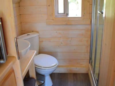 Cabane en bois à Nouvelle-Aquitaine avec salle de bain moderne et fenêtre lumineuse.