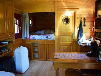Hébergement insolite en roulotte en bois, intérieur chaleureux avec lit en alcôve.