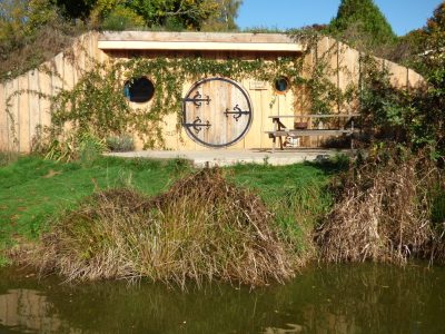 Hébergement insolite en Auvergne : cabane en bois avec porte ronde et vue sur leau.