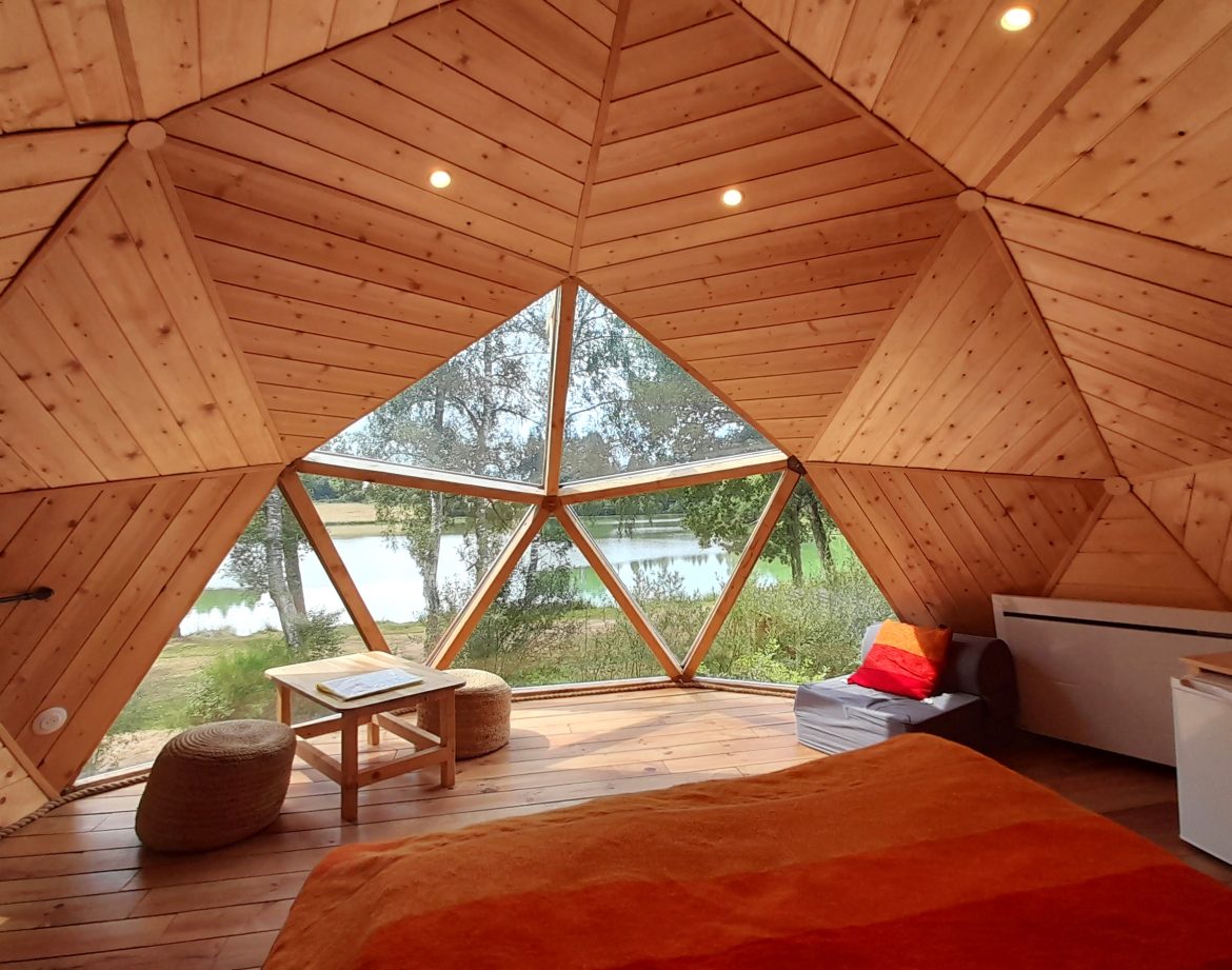 Hébergement insolite en dôme en Auvergne, avec vue sur un lac et intérieur en bois chaleureux.