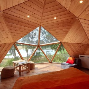 Hébergement insolite en dôme en Auvergne, avec vue sur un lac et intérieur en bois chaleureux.