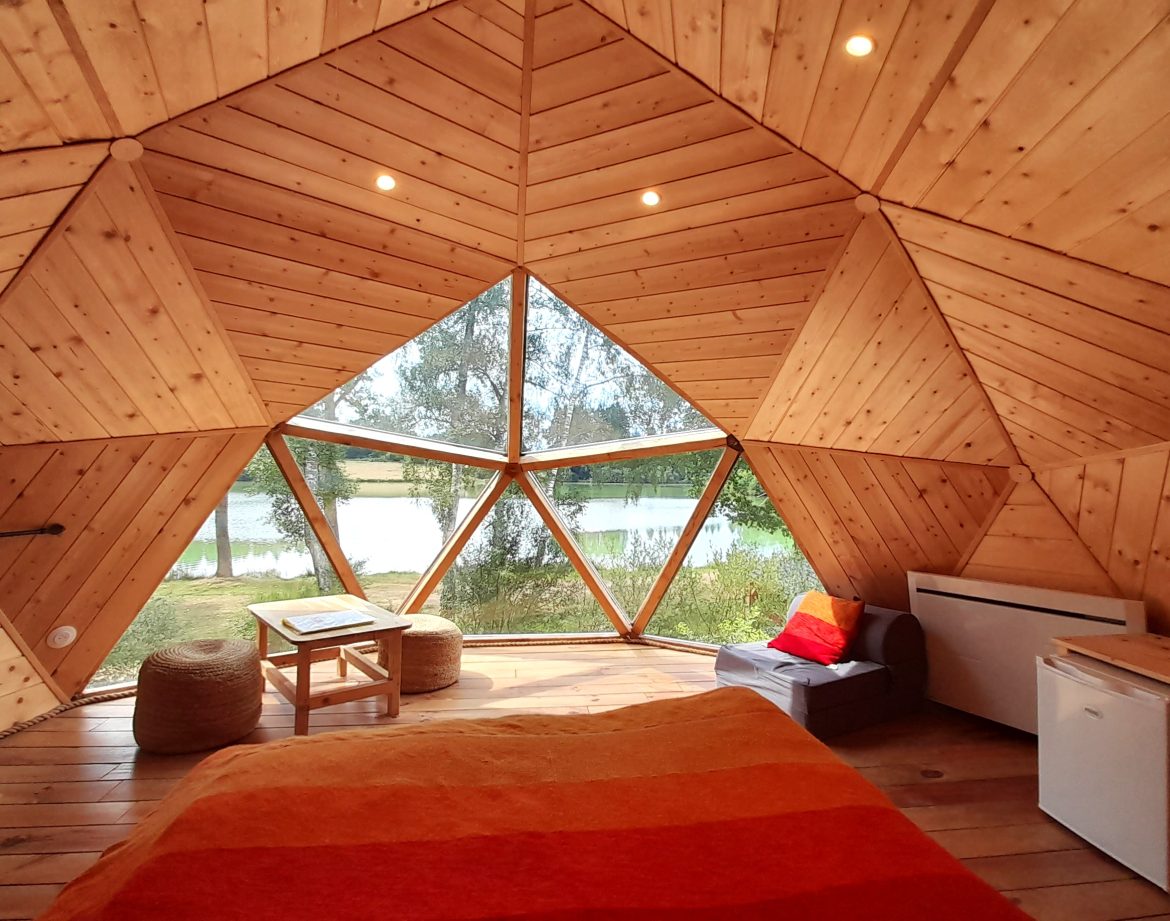 Hébergement insolite en forme de dôme en bois, vue sur le lac depuis la chambre.