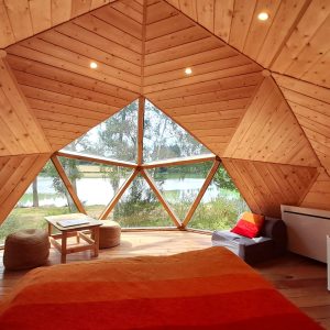 Hébergement insolite en forme de dôme en bois, vue sur le lac depuis la chambre.