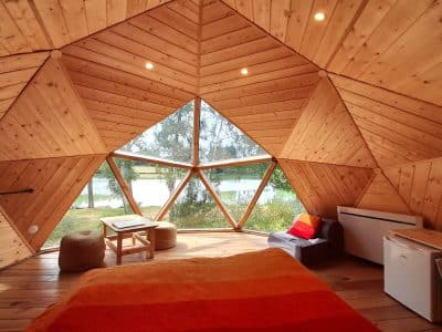 Hébergement insolite en forme de dôme en bois, vue sur le lac depuis la chambre.