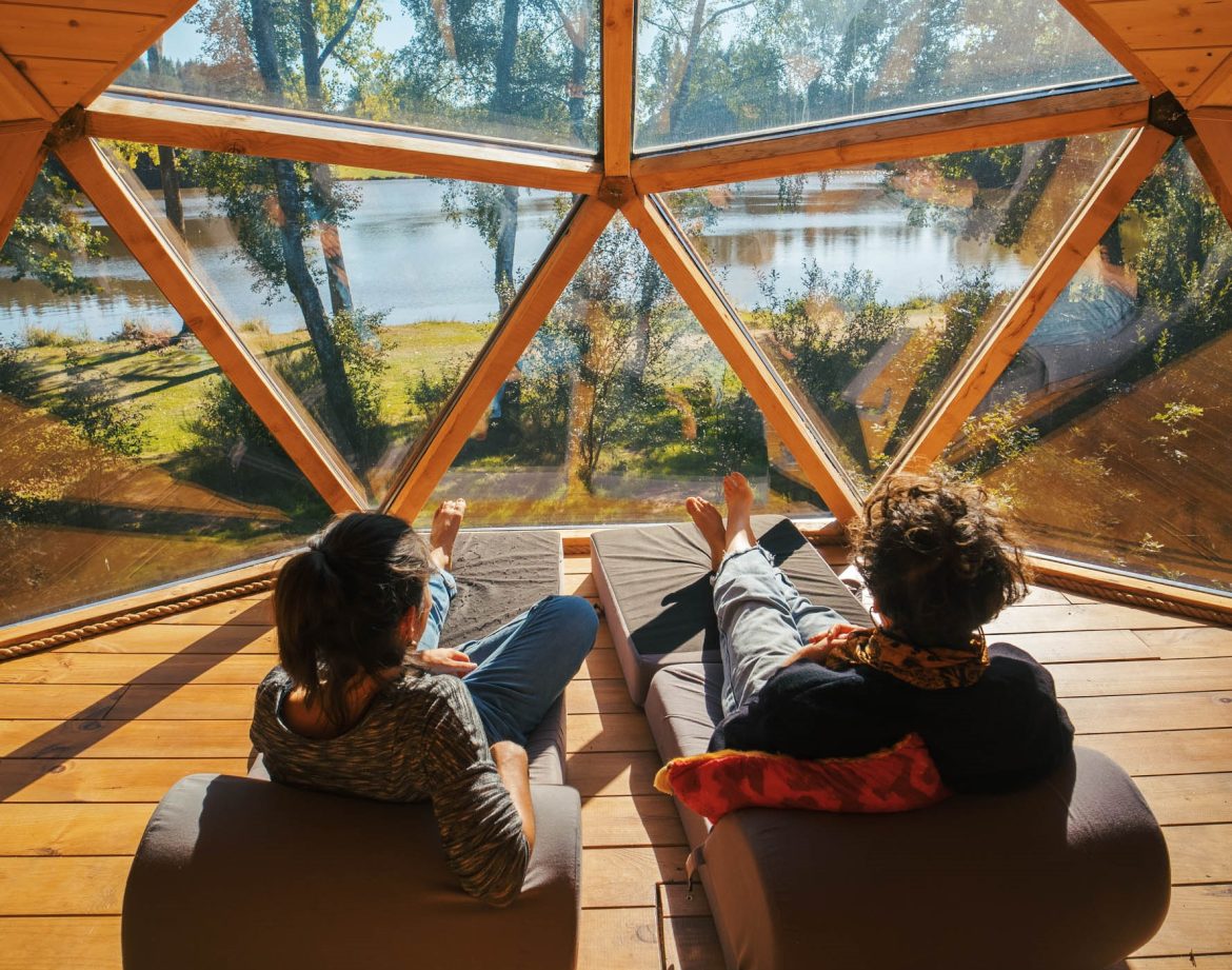 Dôme géodésique en Auvergne, avec vue panoramique sur un lac et la nature environnante.