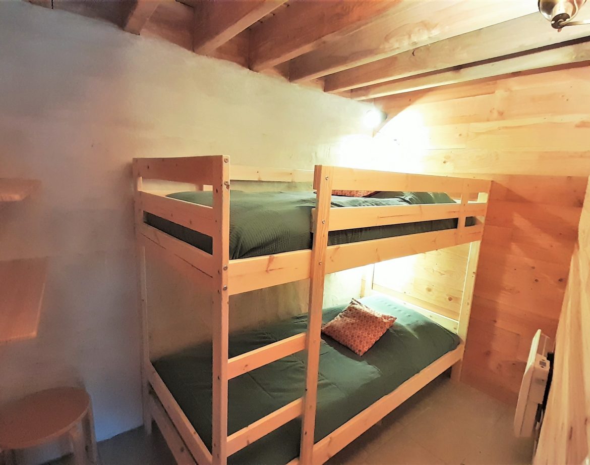 Chalet en bois avec lits superposés, ambiance chaleureuse et naturelle en Auvergne.
