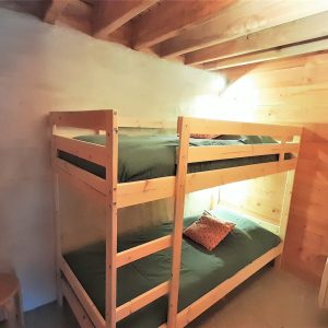 Chalet en bois avec lits superposés, ambiance chaleureuse et naturelle en Auvergne.