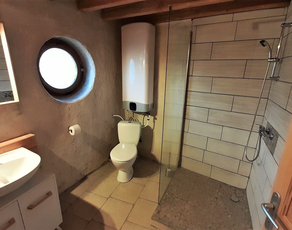 Salle de bain moderne dun hébergement insolite en Auvergne, avec douche et miroir rond.