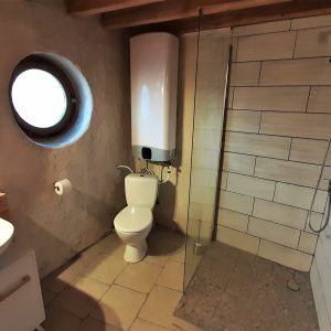 Salle de bain moderne dun hébergement insolite en Auvergne, avec douche et miroir rond.