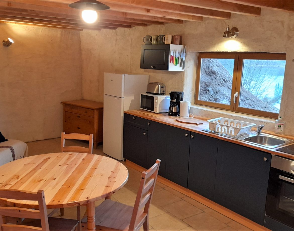 Hébergement insolite en Auvergne : cuisine chaleureuse avec murs en terre et mobilier en bois.
