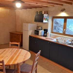 Hébergement insolite en Auvergne : cuisine chaleureuse avec murs en terre et mobilier en bois.