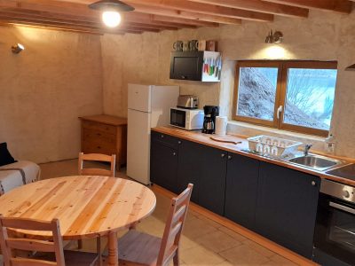 Hébergement insolite en Auvergne : cuisine chaleureuse avec murs en terre et mobilier en bois.